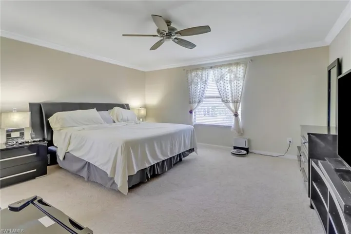 Bedroom with ornamental molding, ceiling fan, and light colored carpet