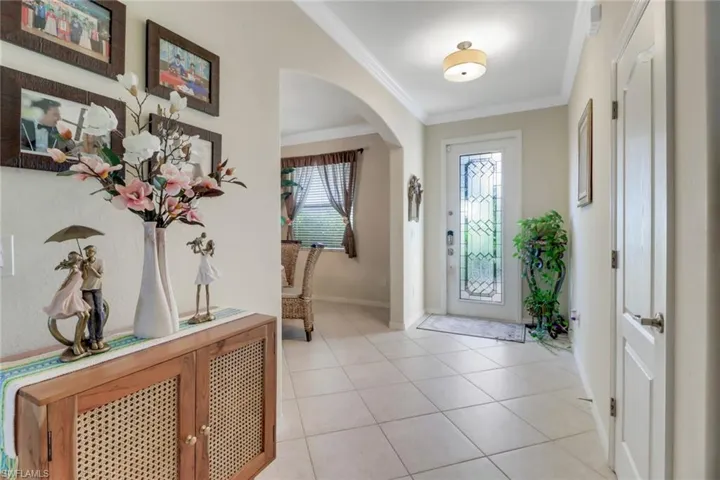 Foyer with light tile patterned floors and ornamental molding