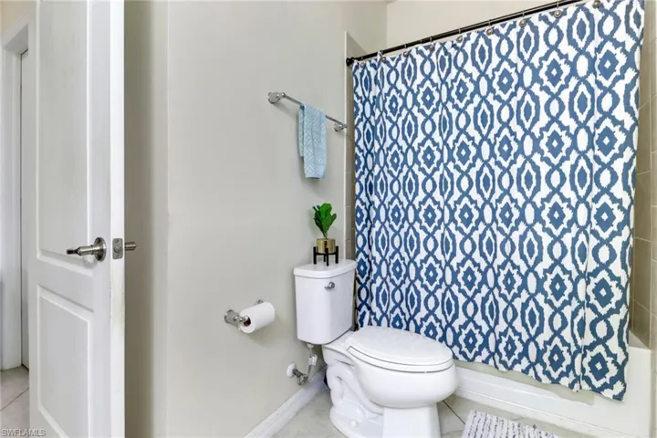 Bathroom featuring tile patterned flooring, toilet, and shower / tub combo with curtain