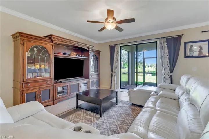 Living room featuring ceiling fan, crown molding, and light tile patterned floors