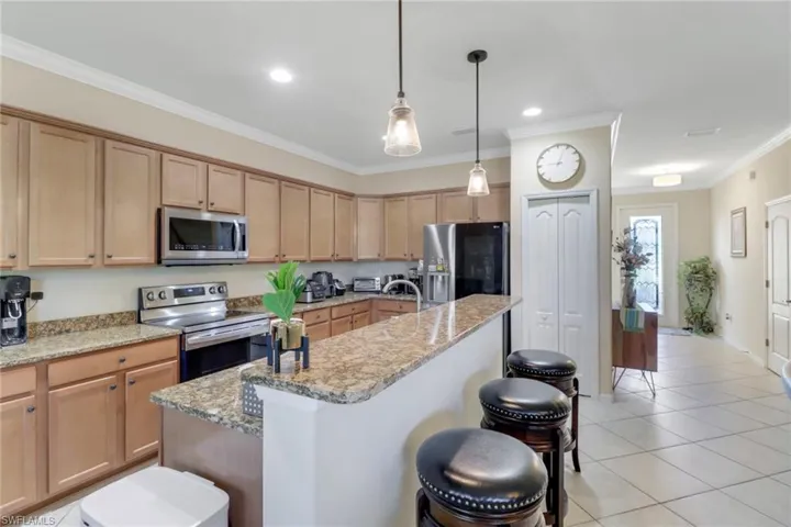 Kitchen featuring a center island with sink, ornamental molding, a breakfast bar area, and stainless steel appliances