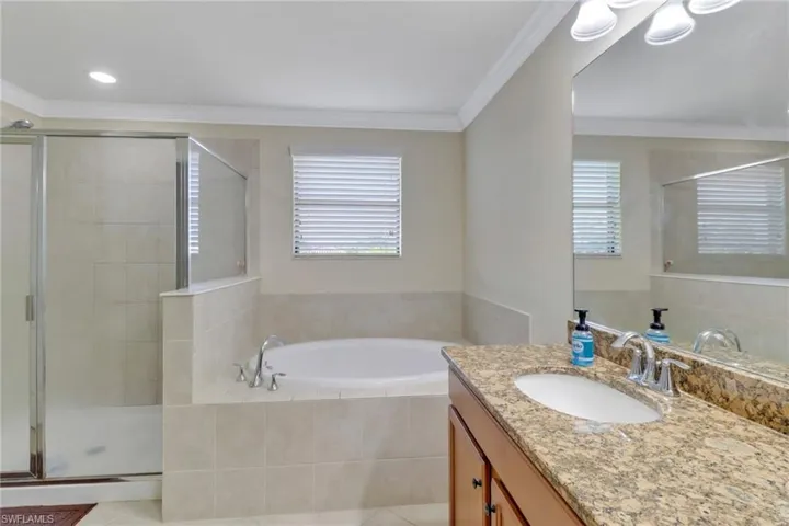 Bathroom with crown molding, vanity, plus walk in shower, and tile patterned floors