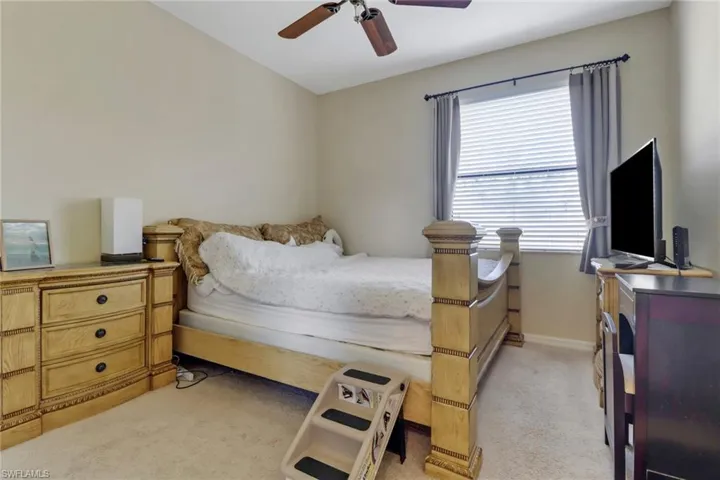 Bedroom with ceiling fan and light carpet