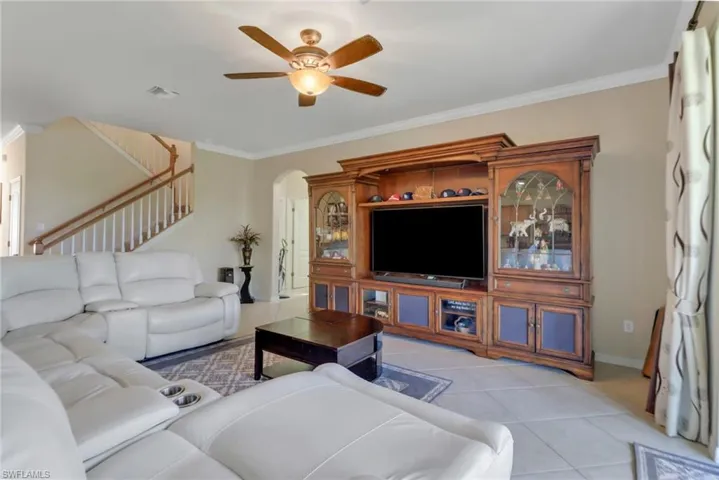 Tiled living room with ornamental molding and ceiling fan