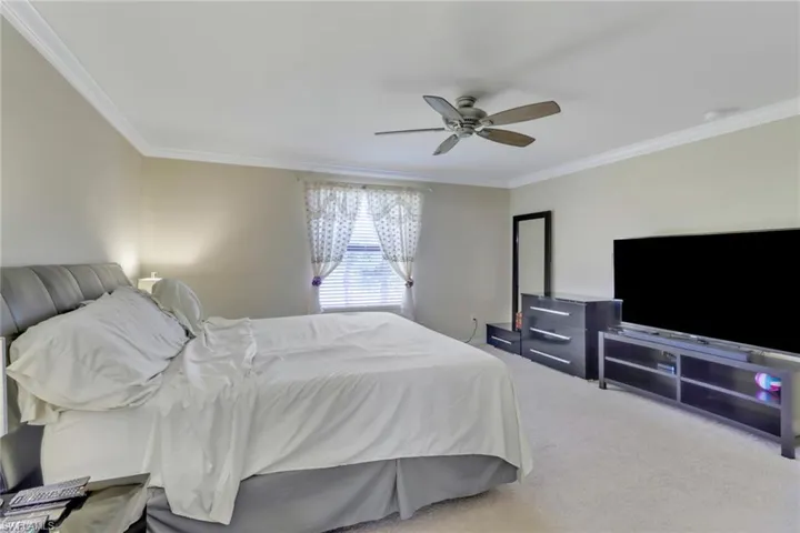 Bedroom with ornamental molding, ceiling fan, and carpet flooring