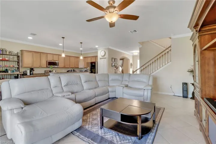 Living room featuring ceiling fan, light tile patterned floors, and crown molding