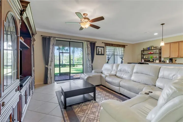 Tiled living room featuring ornamental molding, ceiling fan, and plenty of natural light