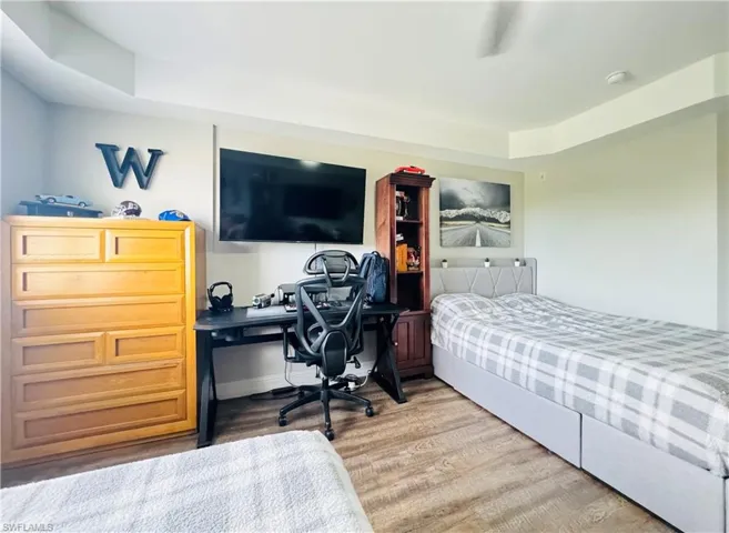 Bedroom with wood-type flooring and a raised ceiling