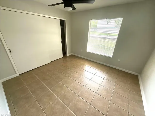 Unfurnished bedroom with a closet, light tile patterned floors, and a ceiling fan