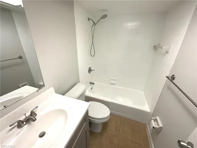 Full bath with  shower combination, vanity, and dark tile patterned flooring