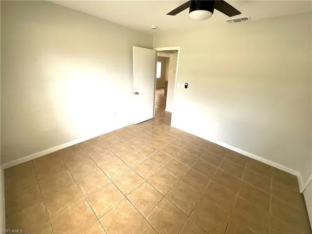 Tiled empty room with baseboards and a ceiling fan