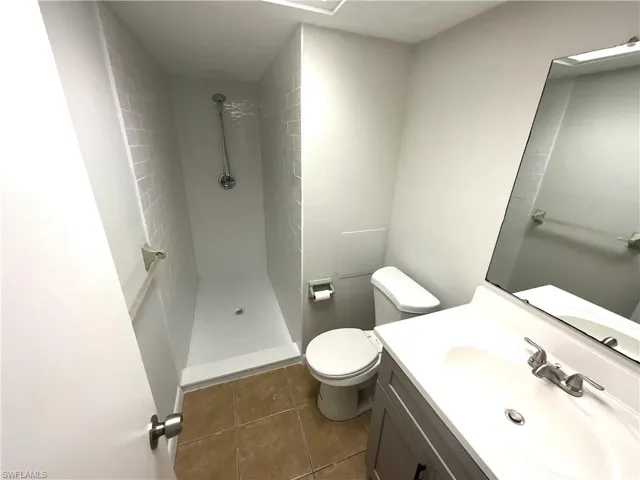 Full bathroom featuring vanity, a shower stall, and dark tile patterned floors