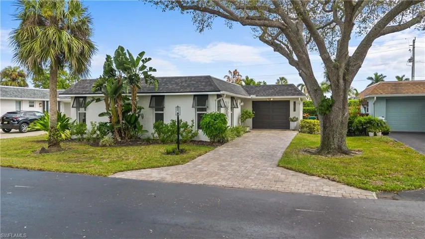 Ranch-style house featuring stucco siding, an attached garage, decorative driveway, a front lawn, and a shingled roof