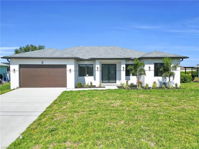 View of front facade with french doors, a front lawn, concrete driveway, an attached garage, and stucco siding