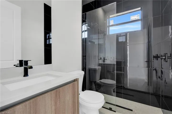 Bathroom featuring vanity, tile patterned flooring, toilet, and tiled shower