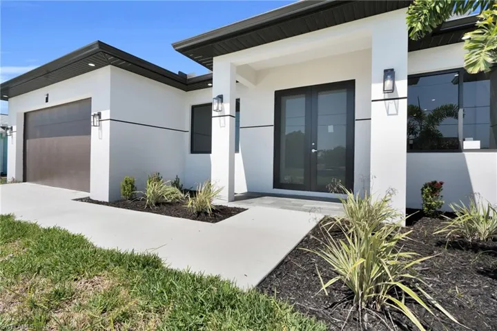Doorway to property with a garage, stucco siding, french doors, and concrete driveway