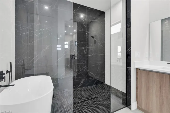 Bathroom featuring tile walls, a shower stall, a soaking tub, and vanity