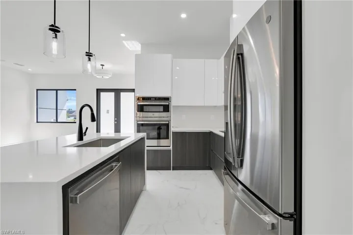 Kitchen featuring light countertops, a sink, appliances with stainless steel finishes, and modern cabinets