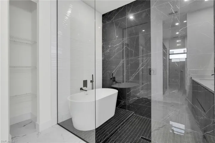 Full bath with a walk in shower, marble finish floor, a walk in closet, and a soaking tub