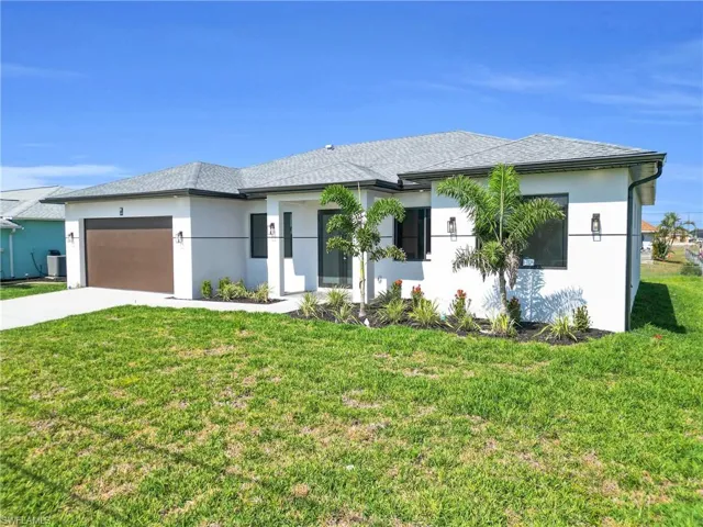 View of front of house featuring an attached garage, driveway, a front lawn, and stucco siding