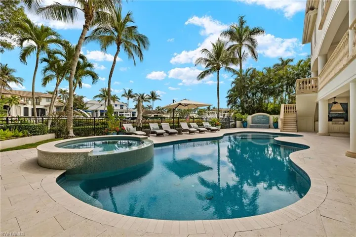 View of swimming pool with a pool with connected hot tub, stairs, fence, and a patio