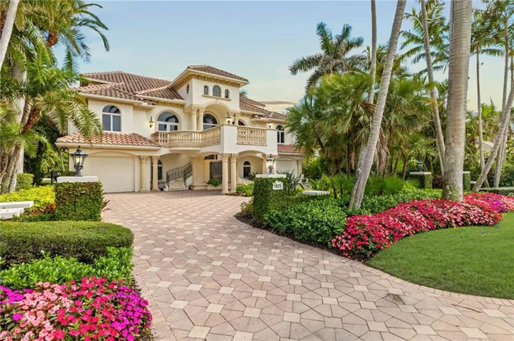 Mediterranean / spanish-style house featuring an attached garage, a balcony, a tiled roof, decorative driveway, and stucco siding