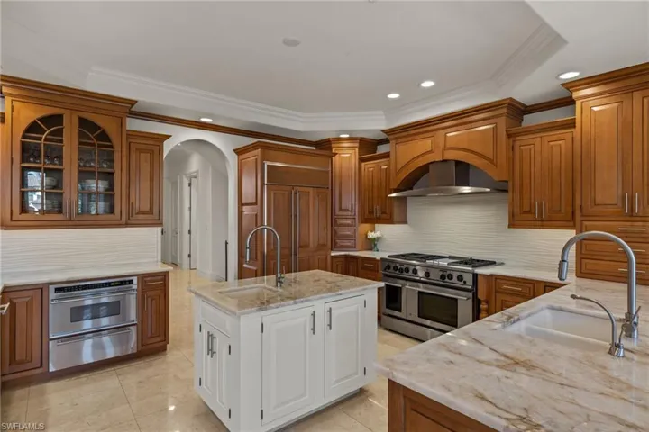 Kitchen featuring premium appliances, brown cabinetry, a sink, and a warming drawer