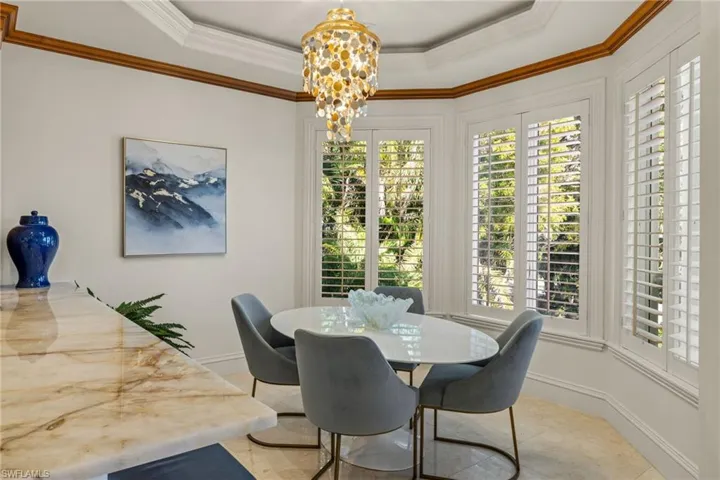 Dining space with baseboards, a chandelier, a raised ceiling, and crown molding