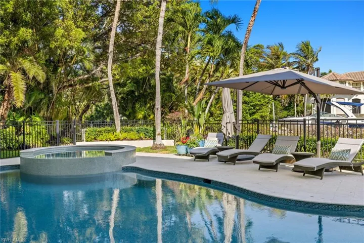 View of pool featuring a pool with connected hot tub, fence, and a patio
