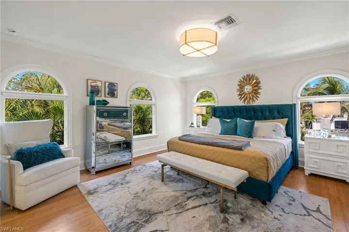 Bedroom featuring baseboards, visible vents, wood finished floors, and ornamental molding