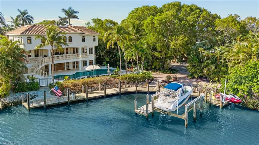 Dock area with a water view, boat lift, and an outdoor pool