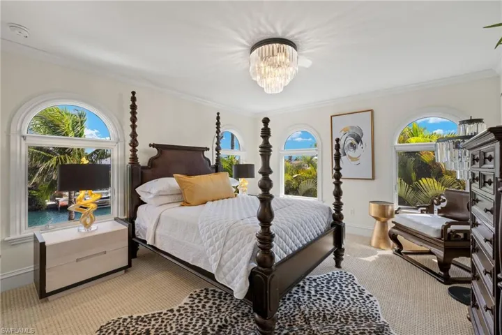 Bedroom with light carpet, ornamental molding, a notable chandelier, and baseboards