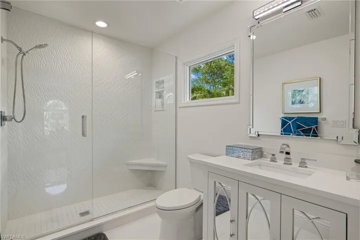 Bathroom featuring a stall shower, visible vents, toilet, vanity, and recessed lighting