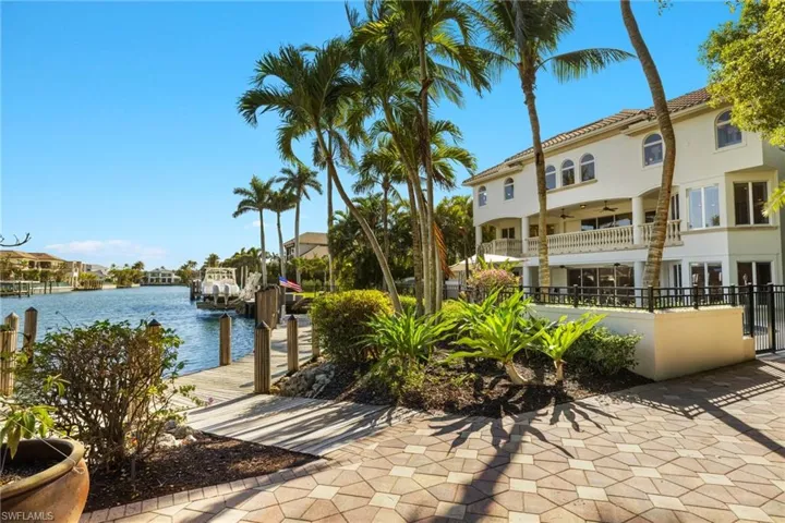 View of patio with a water view, a boat dock, a balcony, and ceiling fan