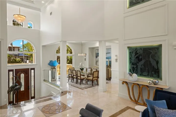 Entrance foyer with baseboards, marble finish floor, a high ceiling, and crown molding