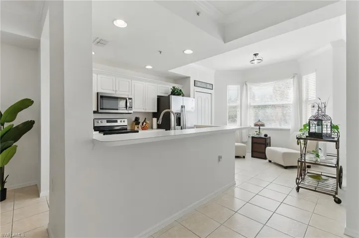 Kitchen with crown molding, a peninsula, stainless steel appliances, visible vents, and white cabinets