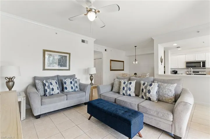 Living area featuring crown molding, ceiling fan, visible vents, and light tile patterned floors