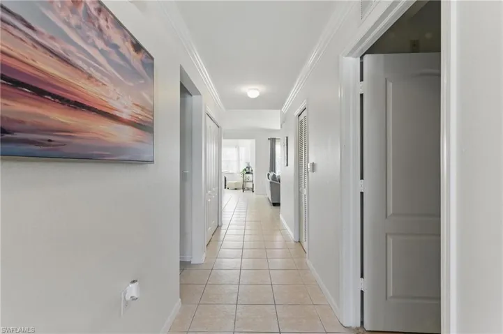 Corridor with baseboards, ornamental molding, and light tile patterned floors