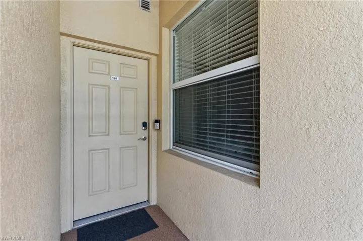 View of exterior entry featuring stucco siding and visible vents