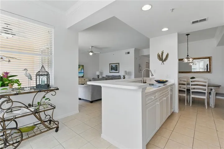 Kitchen with light tile patterned flooring, visible vents, ceiling fan, and ornamental molding