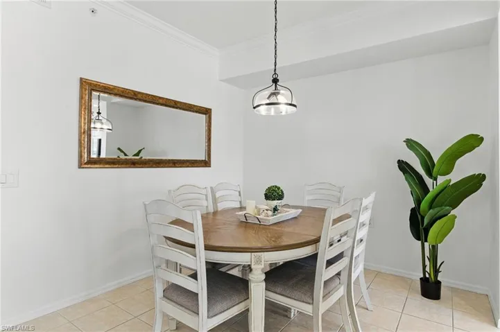 Dining room featuring light tile patterned floors, baseboards, and crown molding