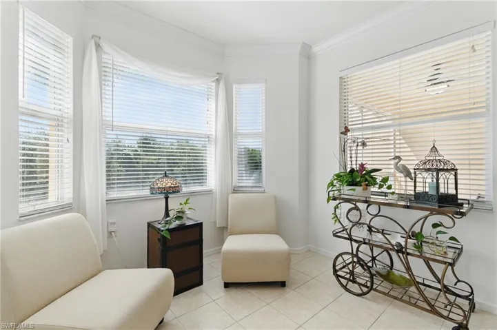 Living area featuring tile patterned flooring, ornamental molding, and baseboards