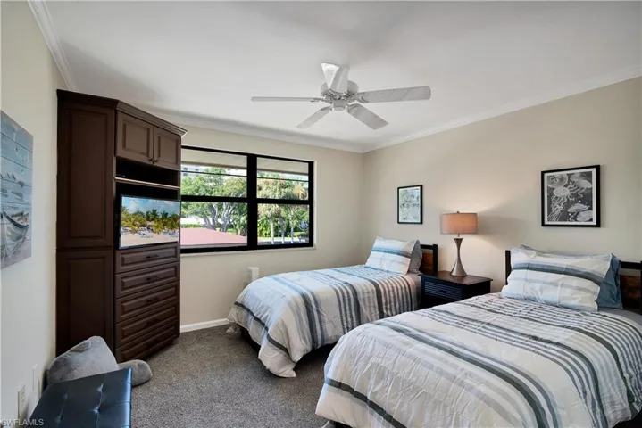 Bedroom with ornamental molding, dark carpet, and a ceiling fan
