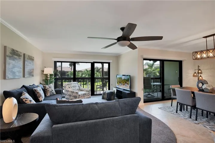 Living room with plenty of natural light, crown molding, light tile patterned floors, and ceiling fan