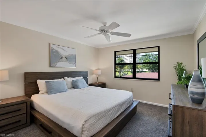 Bedroom with dark carpet, a ceiling fan, and ornamental molding