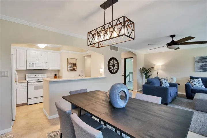 Dining space with a ceiling fan, arched walkways, and ornamental molding