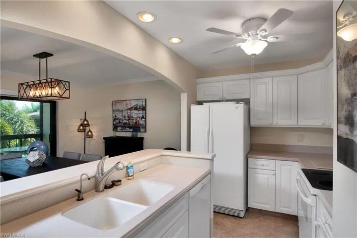 Kitchen with white appliances, white cabinets, light countertops, hanging light fixtures, and recessed lighting