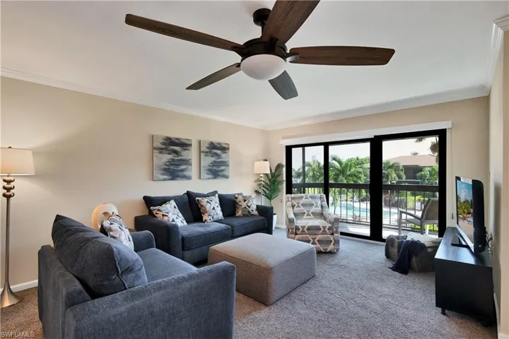 Carpeted living area with crown molding and a ceiling fan