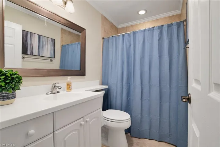 Full bathroom featuring a shower with curtain, vanity, and ornamental molding