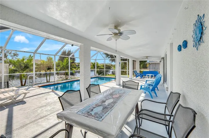 Outdoor pool featuring a sunroom, a patio area, outdoor dining area, and a lanai